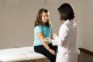 girl having her blood drawn on exam table